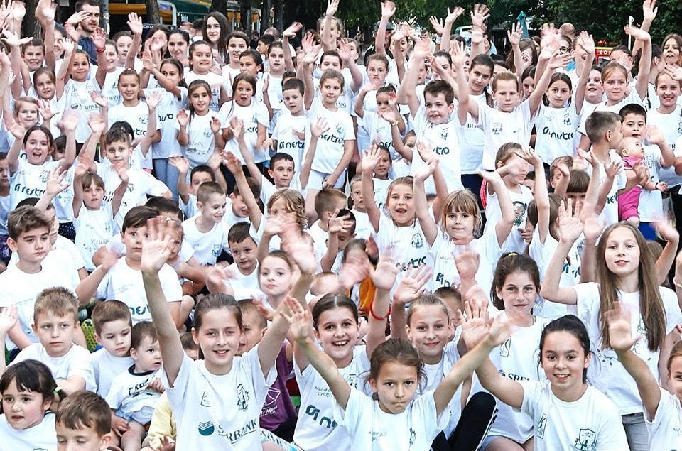 Hundreds of children in club shirts waving at a community youth sports day organised by the club
